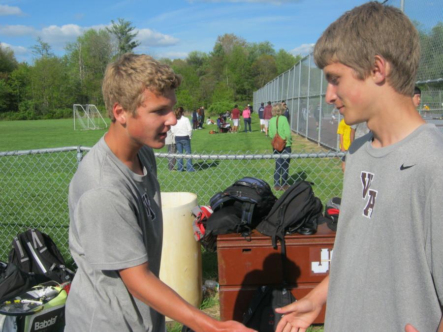 Varsity member Christian Colomb receives a congratulatory handshake from a teammate after winning his match