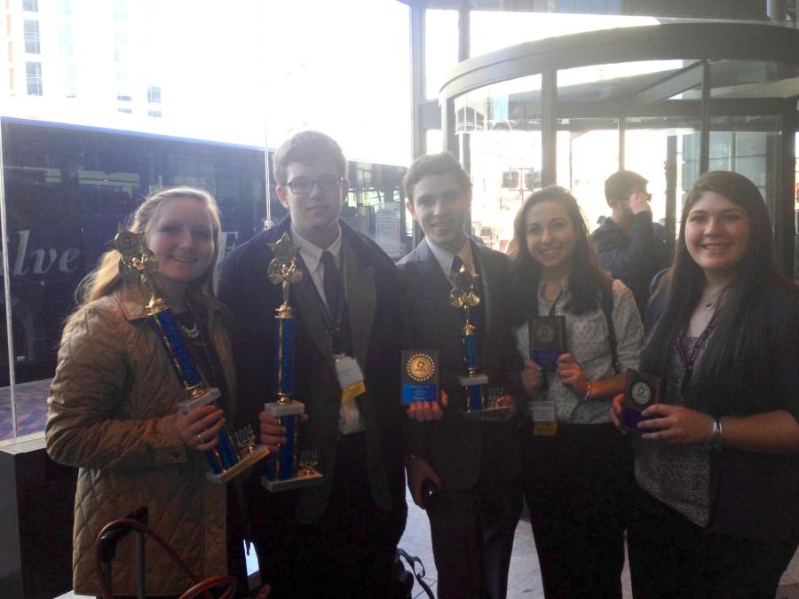 Winning+DECA+members+pose+with+their+trophies+and+plaques.