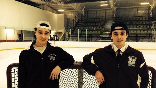 The Curran brothers in front of a hockey rink