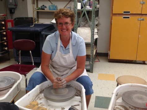Cook sitting at the pottery wheel in the ceramics room.