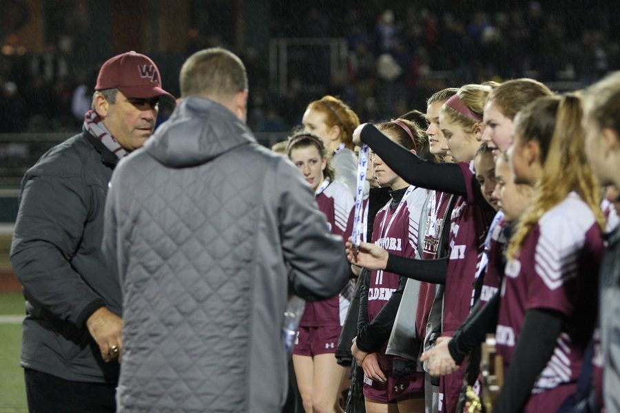 Principal Jim Antonelli hand out finalist medals to the team after the game