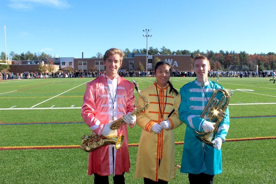 WAs three drum majors, (left to right) Tyler Dillon, Iria Wang, and Brian Carr, pose for a photo during a marching band performance.