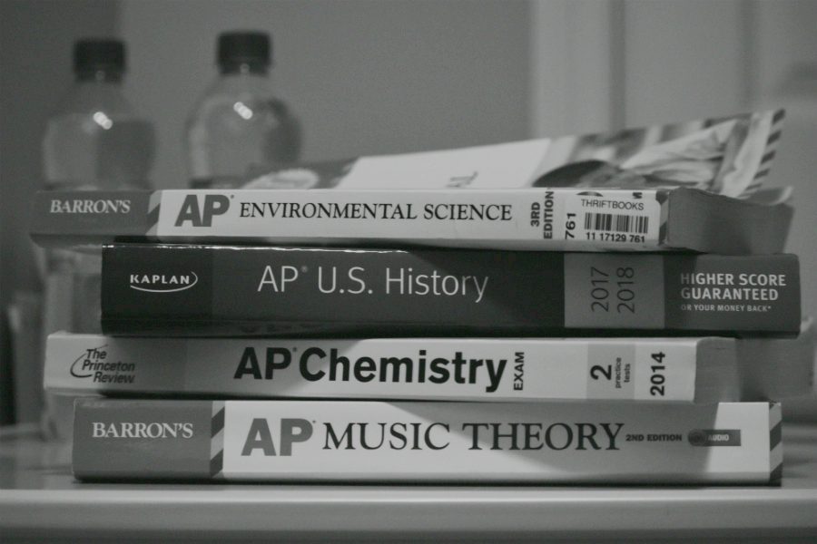 AP prep books pile up on a students desk.