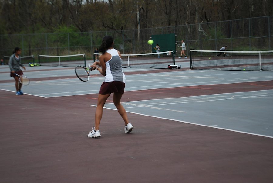 Nithya Sastry preparing to hit the tennis ball back over the net.