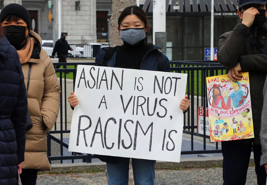 Woman holds an Asian is not a virus, racism is sign during an anti-Asian hate protest. 