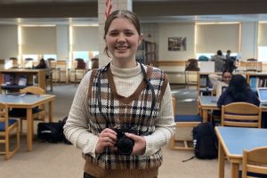 Senior Mairead Ouellette smiles with her camera after being selected for the Drexel Photography Exhibition.