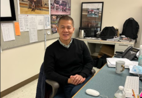 Mr. Eang posing for a picture at his desk.