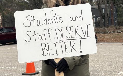 Sign stating students and staff deserve better, held by WEA President Kristine Jussaume. 