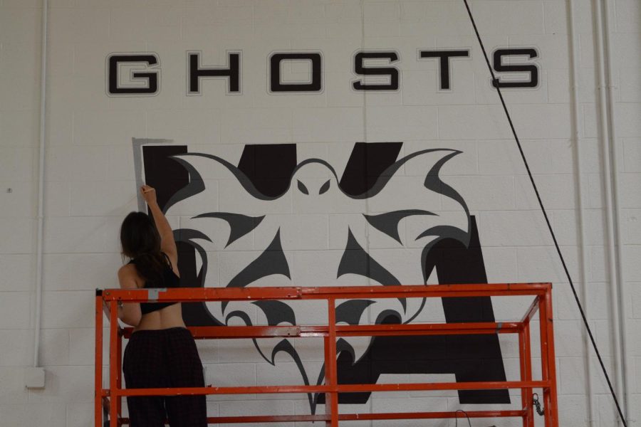 Julia+Donescu+paints+a+design+of+the+new+Ghost+mascot+on+the+wall+of+the+main+gym.