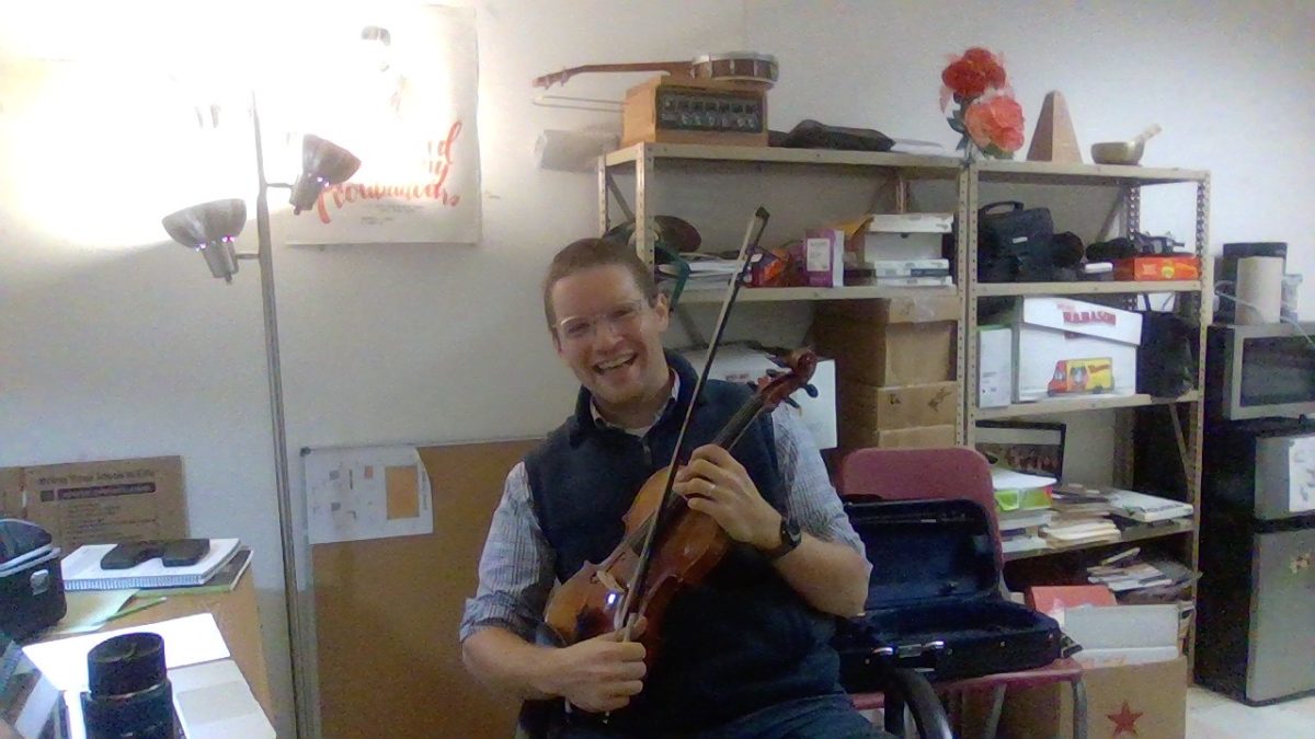Sawyer smiles with his violin in the band room.