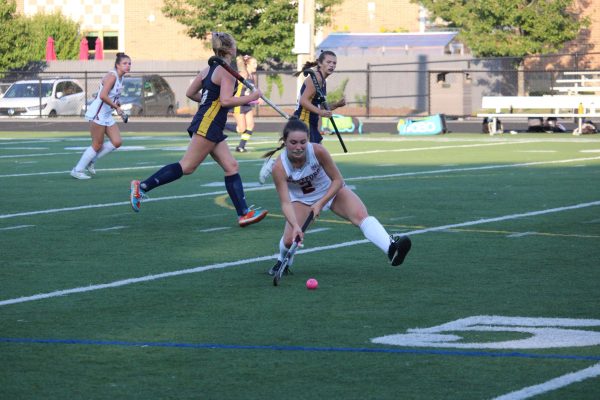 Senior Emily Lux in motion passing the ball up to her teammate in front of her.