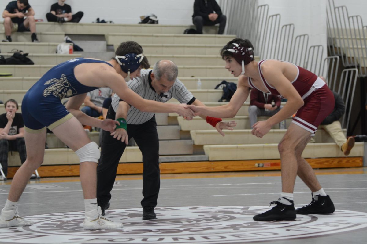 Junior Travis Proulx shakes hands with a Foxborough wrestler seconds before the referee signals the start of their match. 