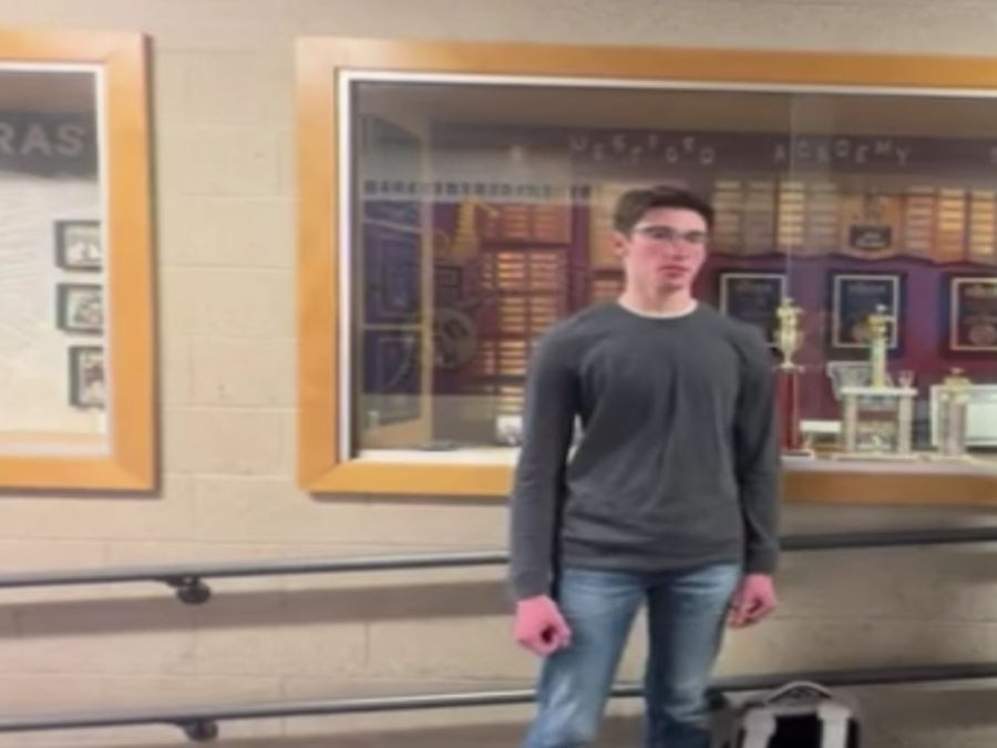 Sophomore Henry Boltz stands next to WA music awards in the band hallway.