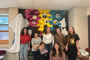 Members of Shakespeare Club pose for a photo in front of their mural. 