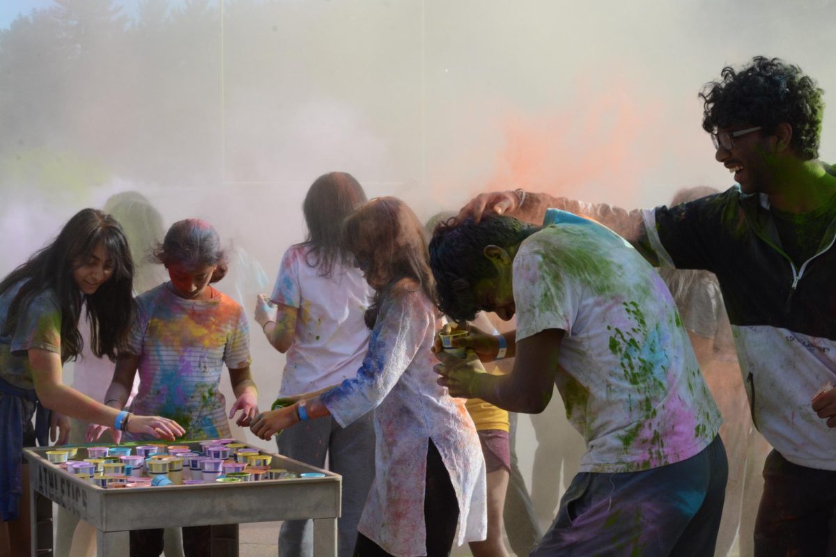 Guests begin throwing Holi colors at each other from cups placed on a cart.