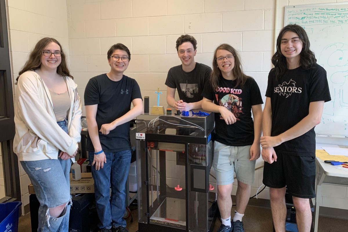 (Left to right) Leaders of the robotics capstone Renée Michaud, Connor Weiss, Nick Franklin,  Jacob Bluestein, and Jonathan Tang pose for a picture in front of one of the 3D printers.
