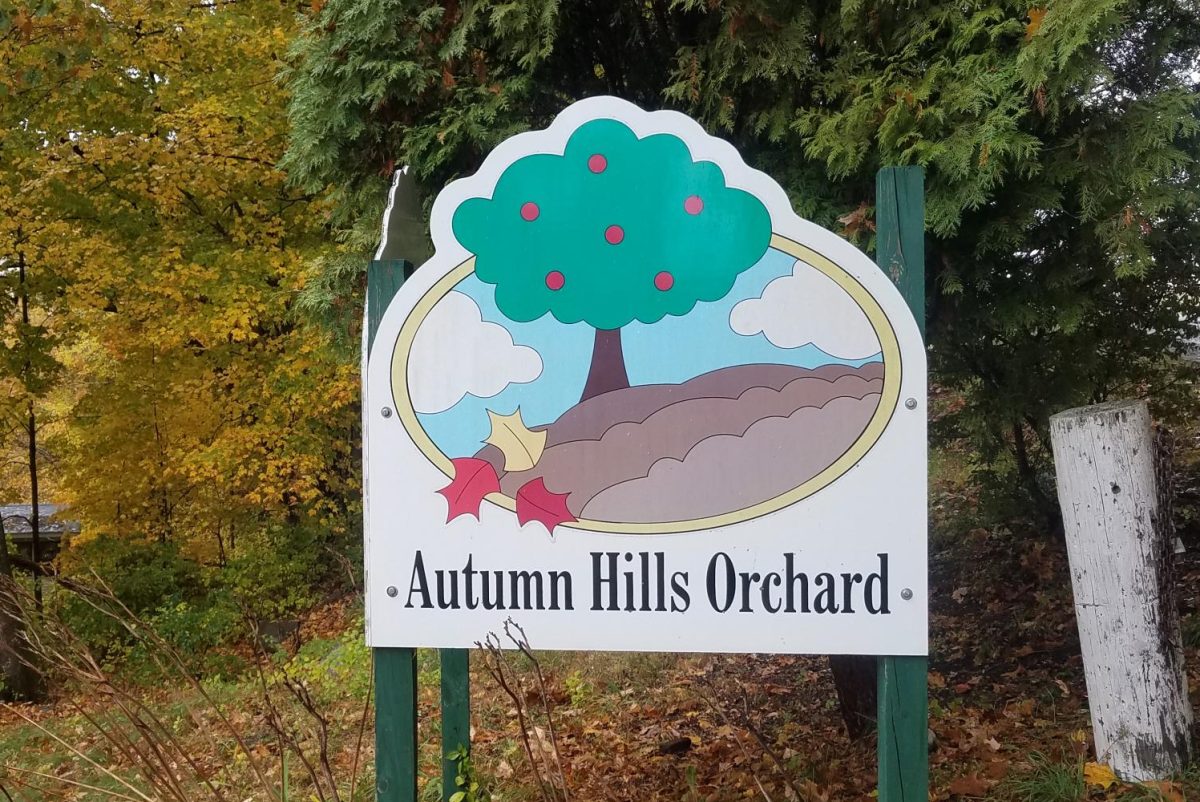 A brightly colored sign is displayed at the entrance of Autumn Hills Orchard.