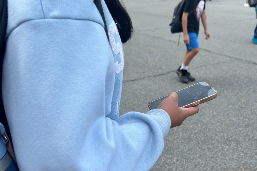 A middle school student checks their phone. 