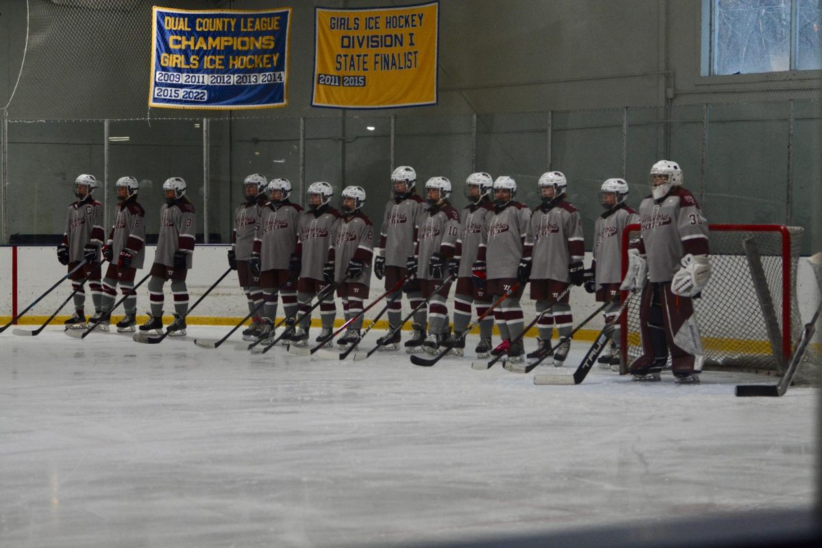 The WA Girls' Ice Hockey team stands together as they wait for the official start of their game against Boston Latin.