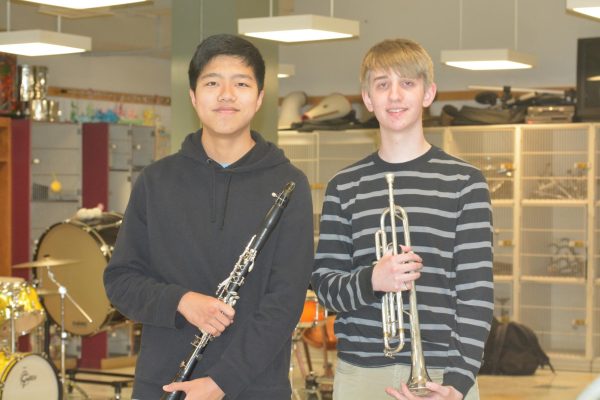 Luke Wang (left) and Daniel Engdahl (right) pose for a photo together in the band room, each holding their respective instrument. 