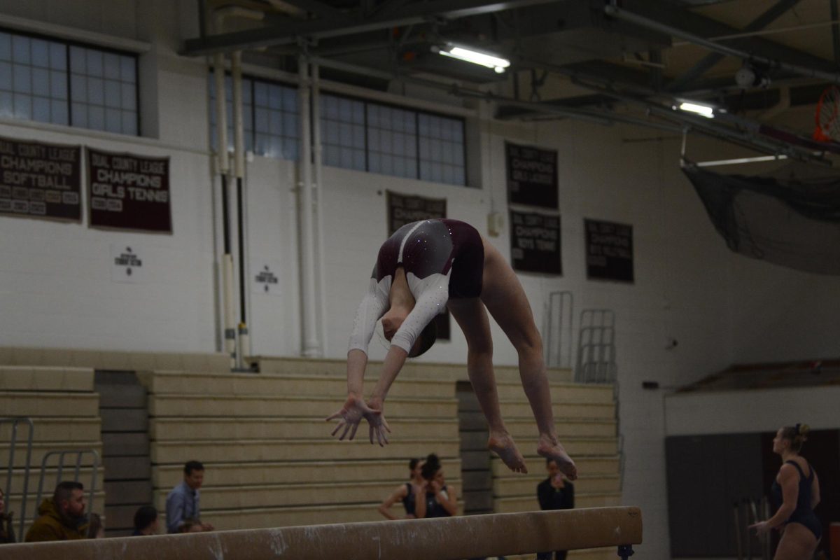 Swanson gracefully executes a back handspring on the beam, earning herself a score of 8.4.