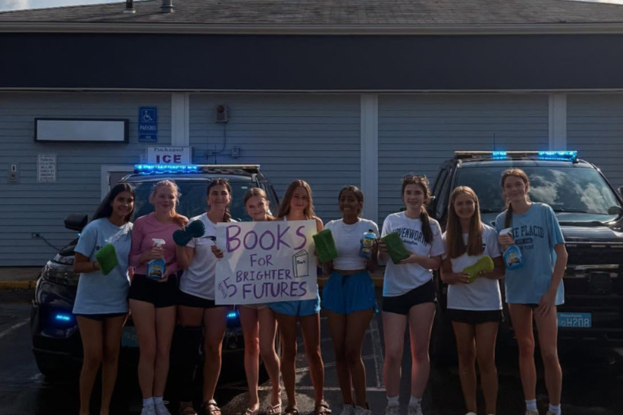 Club members and the founders of Books For Brighter Futures stand together at a promotional event.