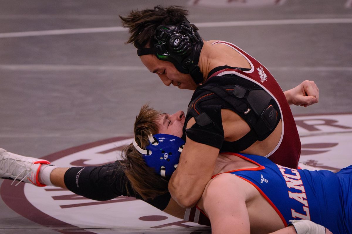 Senior Benjamin Chen wraps his arm around a Londonderry wrestler to maintain a pin.