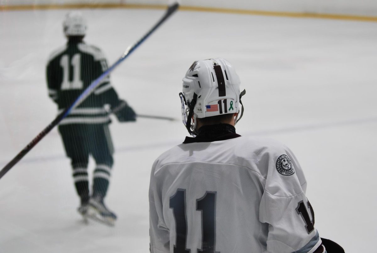Senior forward Ethan Murphy glances at an opposing player as both teams glide into position, ready for the game to begin after a penalty pause. 