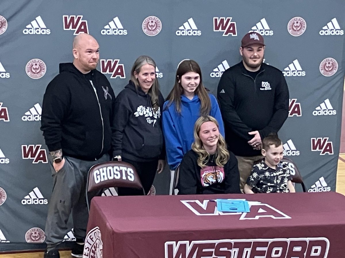 Senior Ella Doran at her Roxbury Community College commitment signing for flag football, surrounded by family and joined by WA Flag Football coach Connor Mclaughlin standing on the right.