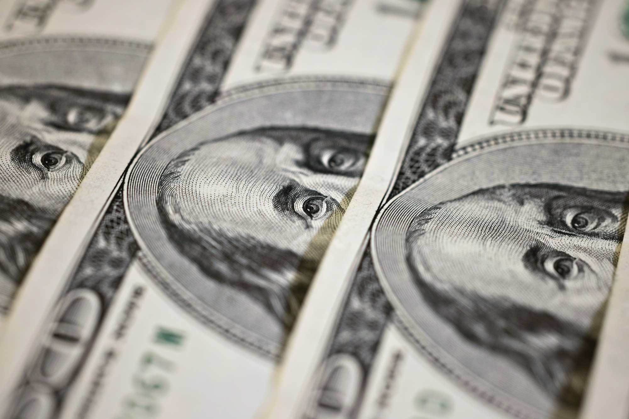 Hundred dollar bills are spread out across a table.