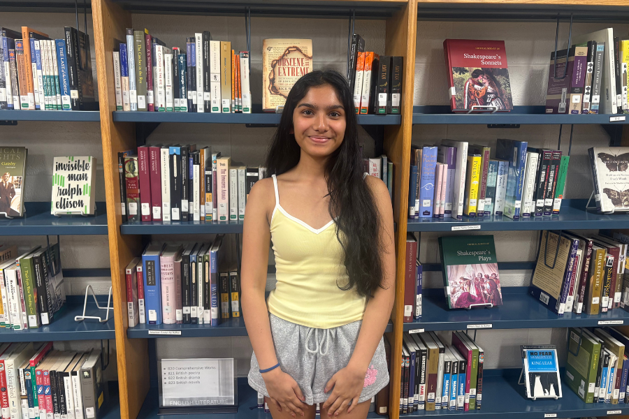 Shah poses for a photo against a bookshelf in the WA library.