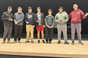 The WA Math Team poses for a photo on stage with their Rubix cube prizes at the State competition.
