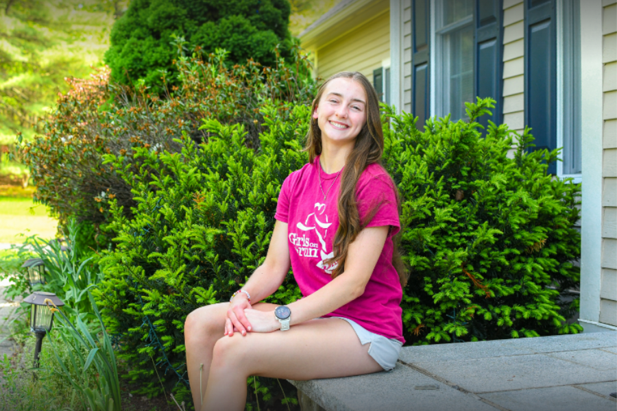 Raker sits on her doorsteps wearing her GOTR coach t-shirt. 