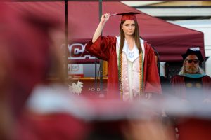 Kelly stands in front of the crowd and instructs the seniors to turn their tassel to the left side, finalizing graduation.